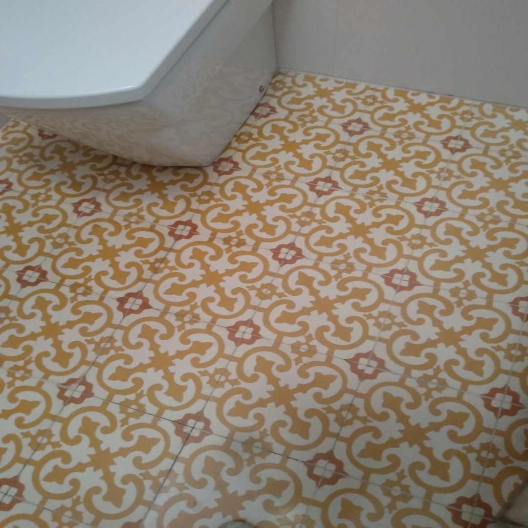 Baño con mosáicos hidráulicos en forma de x y colores rojos y amarillos