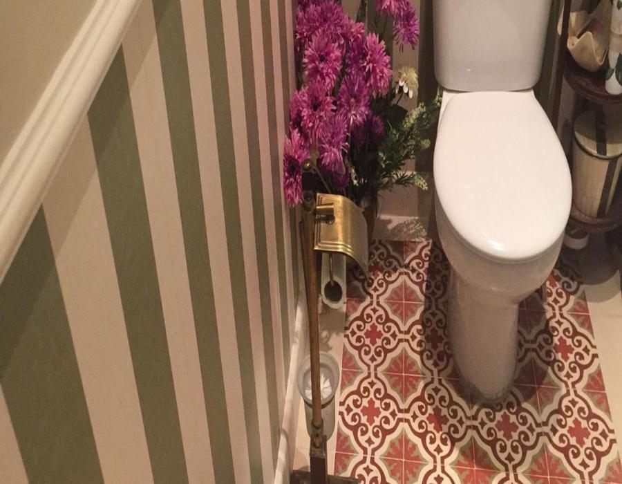 Baño con mosáicos florales hidráulicos en tonos rojos y grises