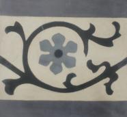 Cenefa mosáico hidráulico con la representación de la flor central en negro y gris